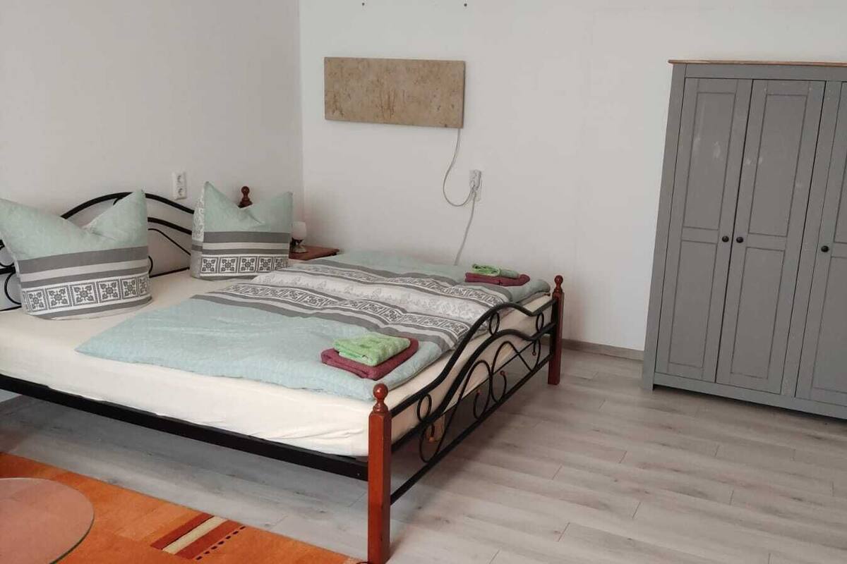 Ein Schlafzimmer mit Bett, Kissen, einem Kleiderschrank und einem kleinen Tisch.