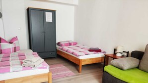 A bedroom with two beds, a wardrobe, a small table with a lamp, and a sofa. - Müllers Gästeunterkunft Gangkofen (Gangkofen)
