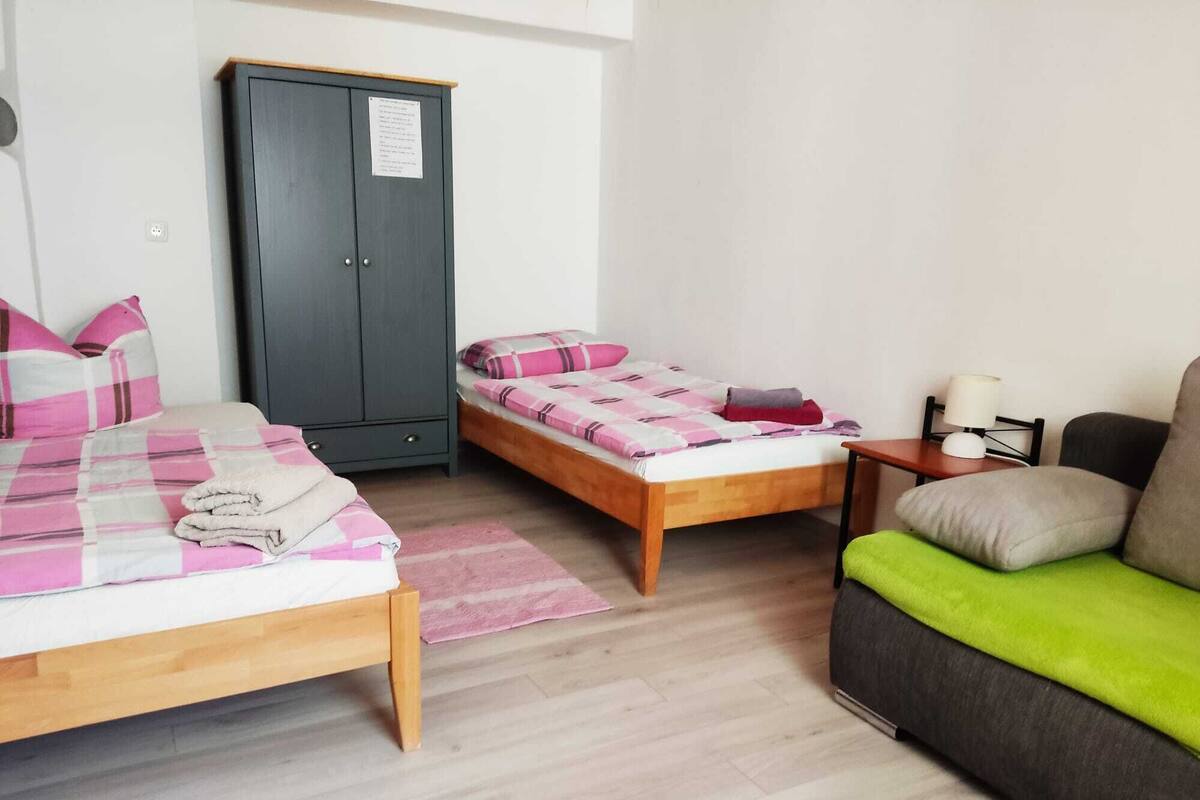 Ein Schlafzimmer mit zwei Betten, einem Kleiderschrank, einem kleinen Tisch mit Lampe und einem Sofa.