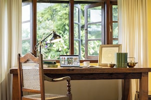 A wooden desk with a laptop, books, a teapot, and a framed picture.