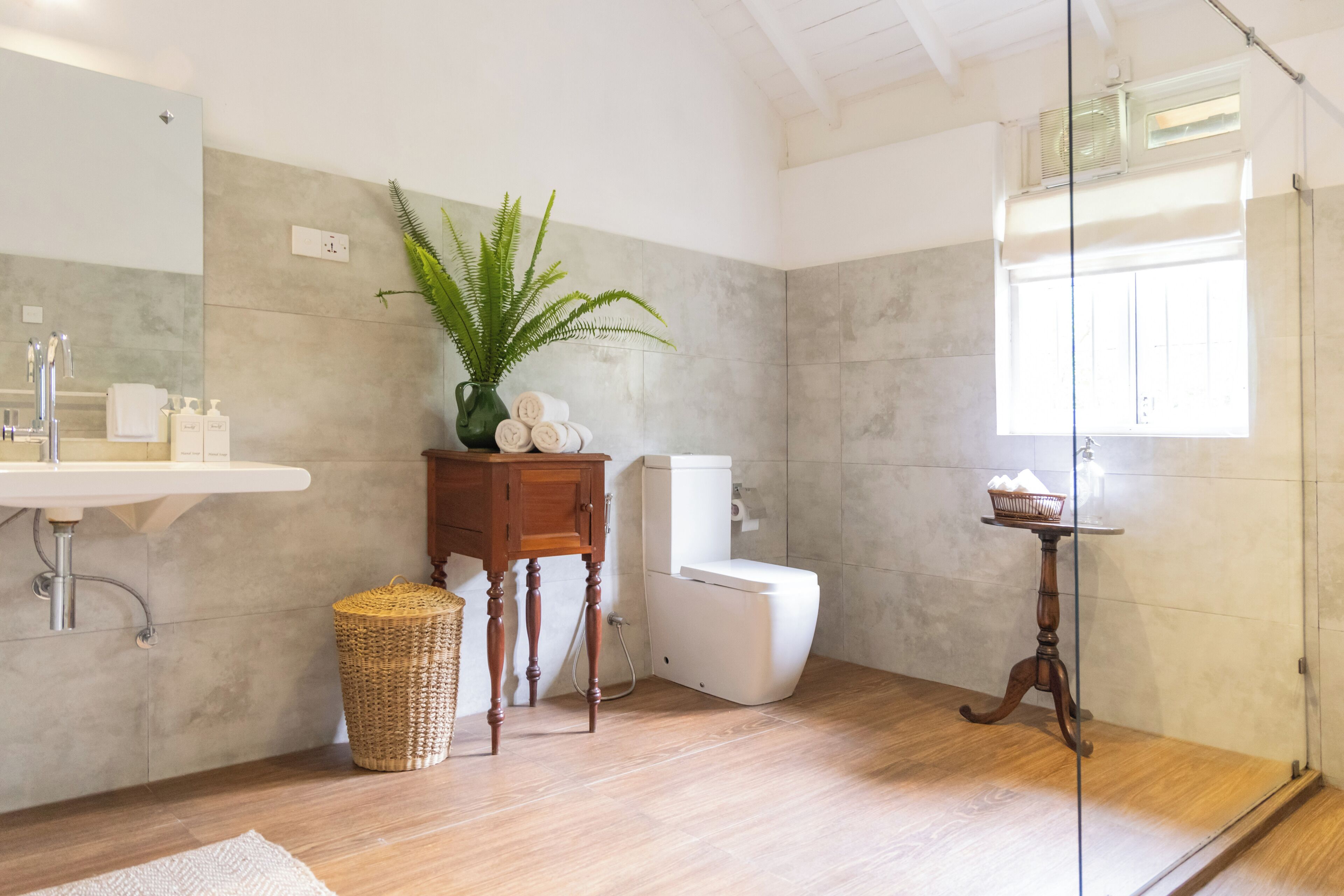 Un baño con tocador de madera, lavamanos, inodoro y zona de ducha.