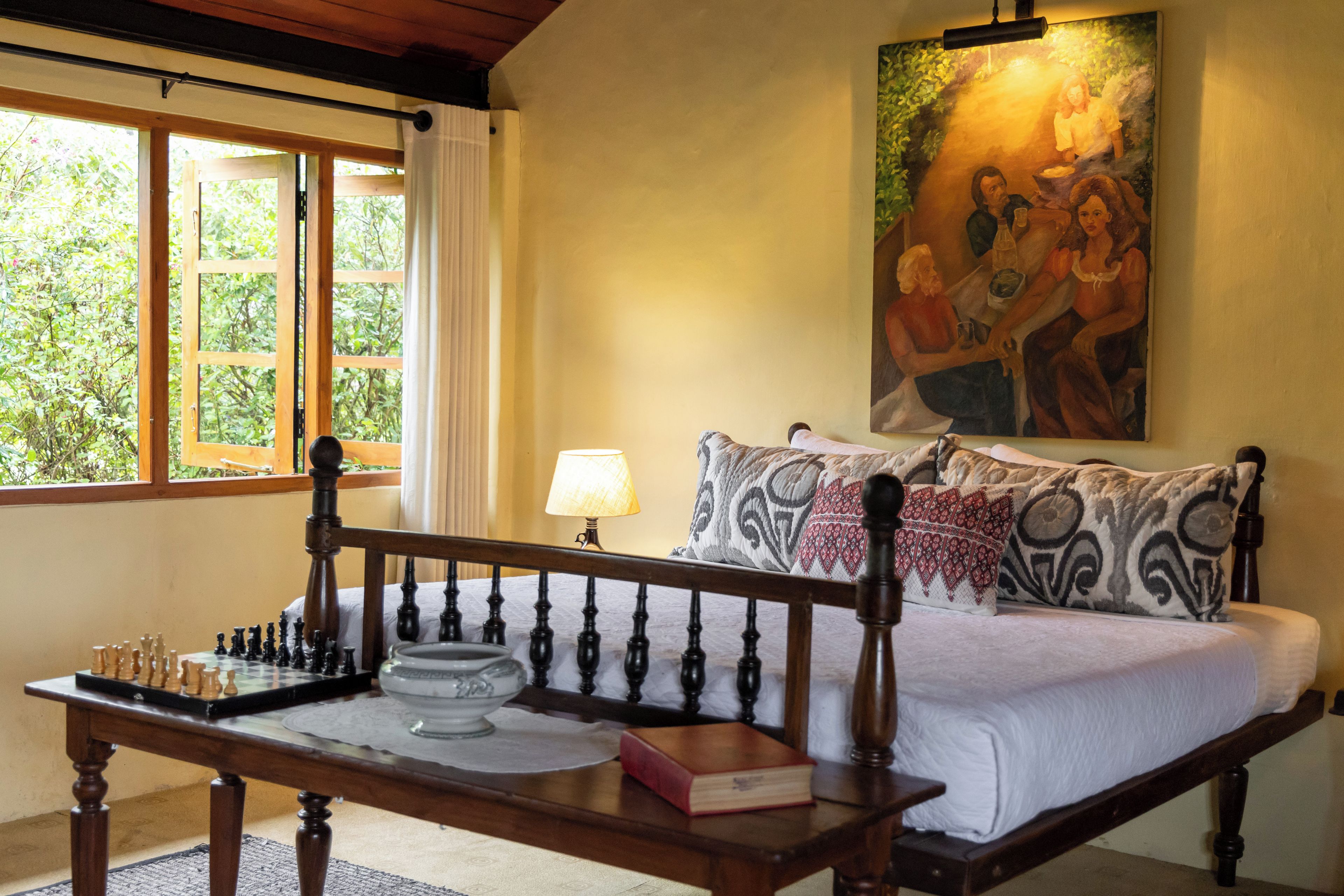 A bedroom with a wooden bed, a chessboard, a book, and a painting on the wall.