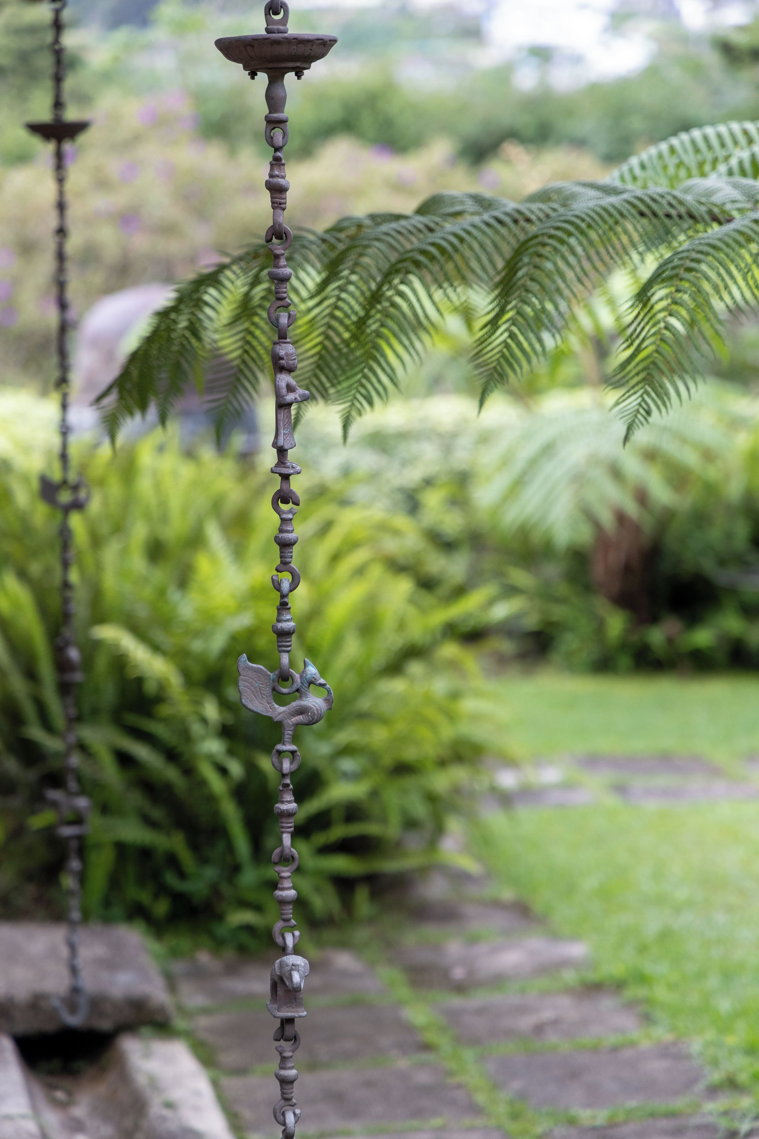 Ein Garten mit einer Metallskulptur, die eine Kette mit Tierfiguren zeigt.