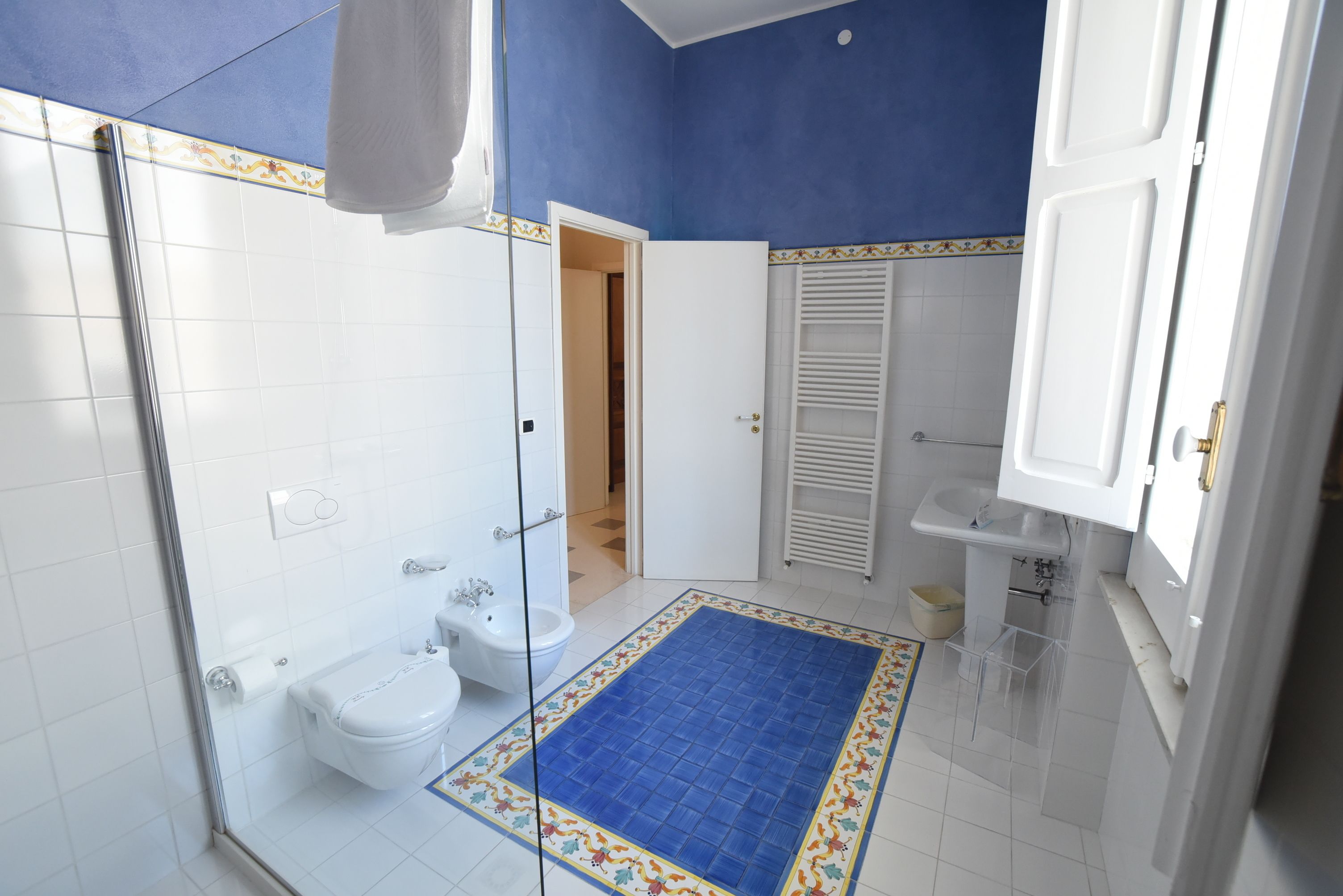 A bathroom with a shower, toilet, bidet, and sink.