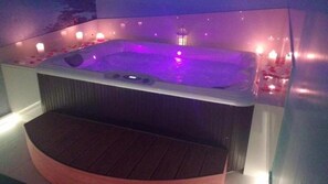 A hot tub with a wooden bench in front, surrounded by candles. - Barone Liberty & Luxury SPA-Boutique Hotel (Gallipoli)