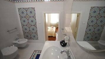A bathroom with a bathtub, two sinks, and a bidet.