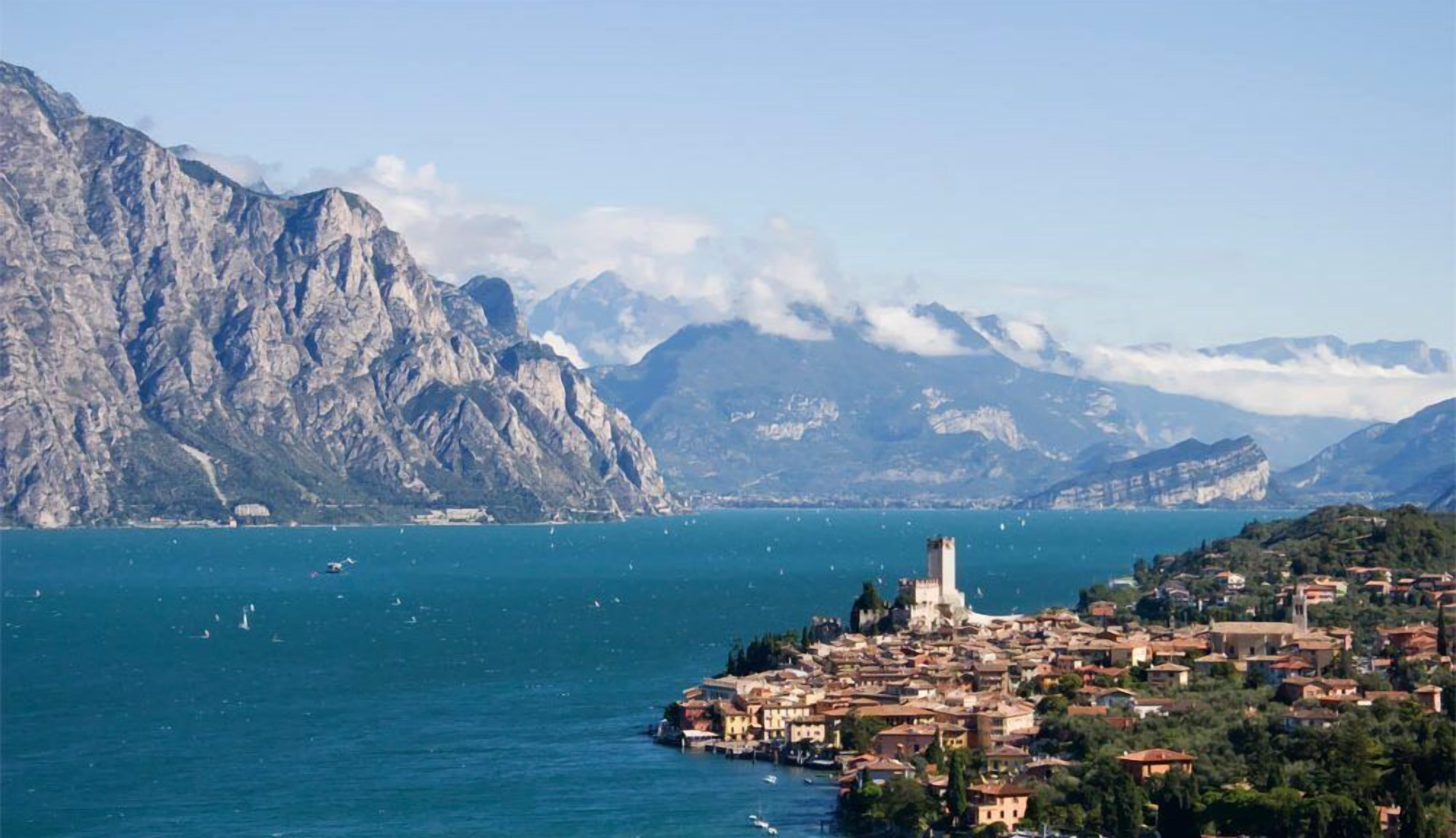A coastal town with a prominent tower, surrounded by mountains and a large body of water.