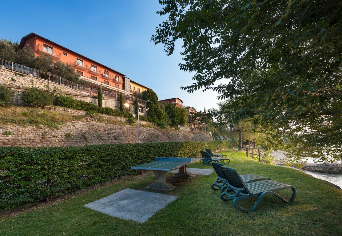An outdoor area with a ping pong table, benches, and a stone wall.