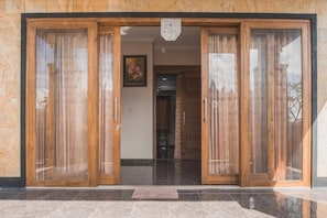 A wooden-framed entrance with glass doors and a tiled floor. - Villa Amari (Penida Island)