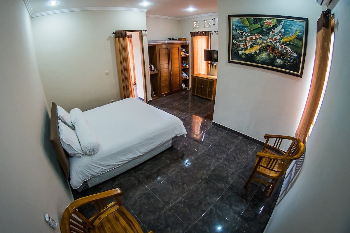 A hotel room with a bed, a desk, a chair, and a painting on the wall.