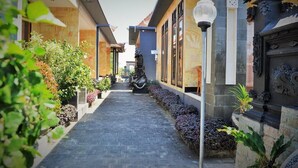 Un sendero estrecho bordeado por edificios con columnas decorativas y plantas.