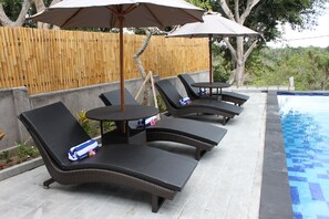 Een buitenzwembad, parasols bij het zwembad en ligstoelen