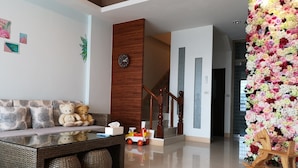 A modern living room with a sofa, a coffee table, a teddy bear, a clock, and a floral wall decoration. - Chance Encounter (Luodong)