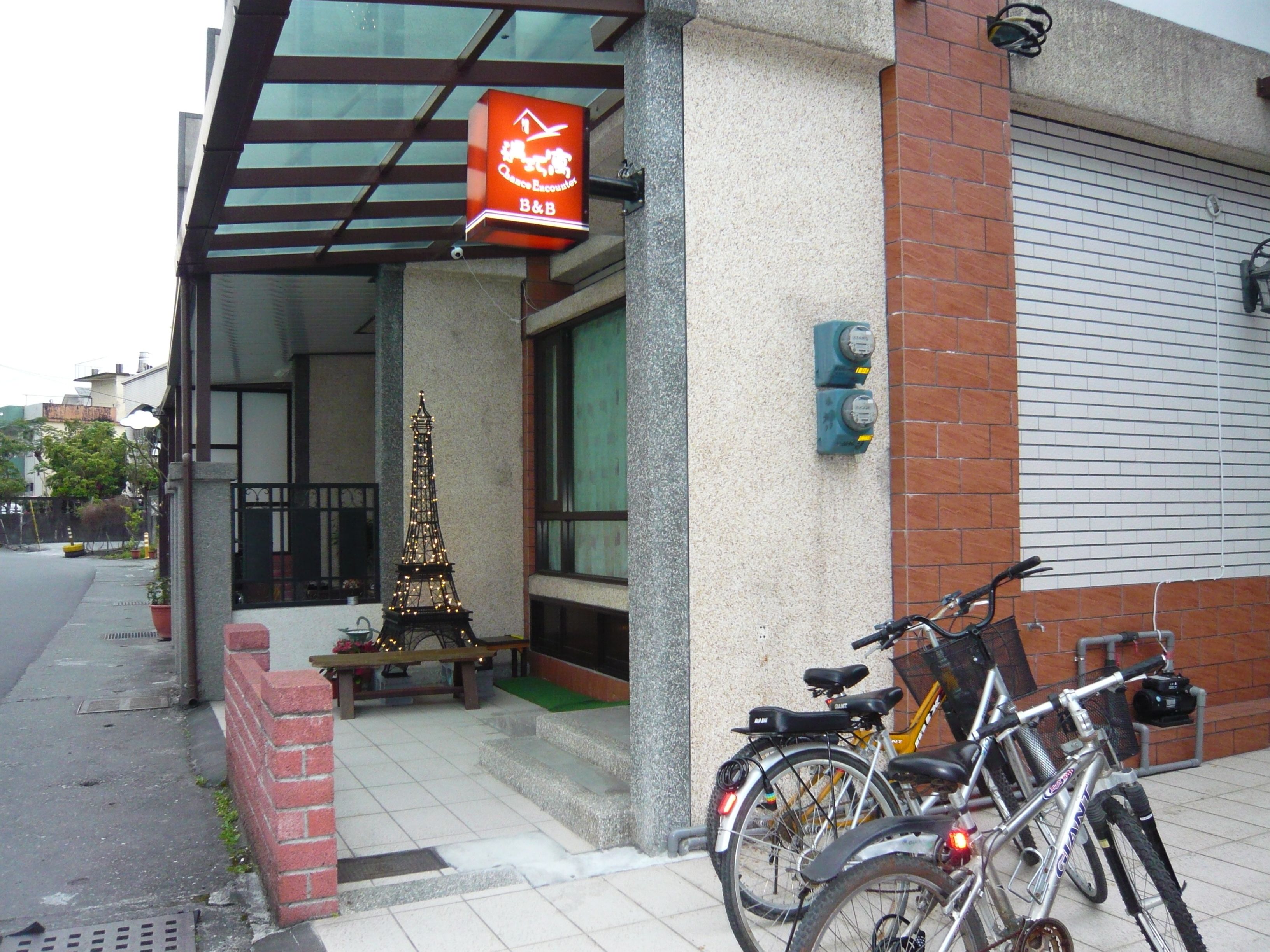 Un edificio con entrada de vidrio, un pequeño espacio de esparcimiento al aire libre y una bicicleta estacionada afuera.
