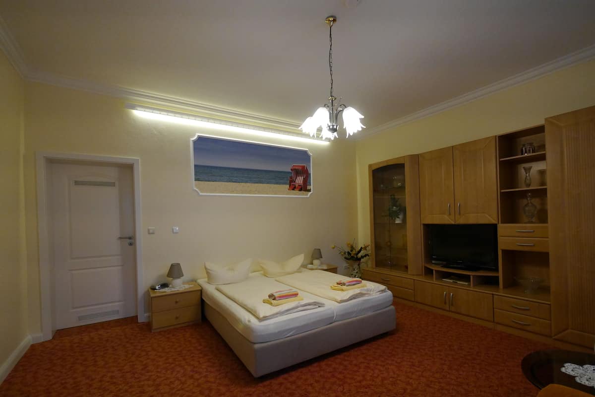 A bedroom with a bed, a nightstand, a lamp, a TV, and a cabinet.
