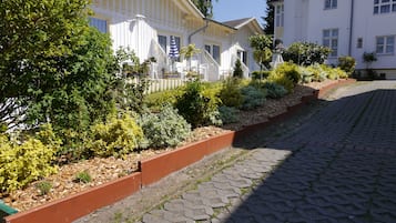 Ein Innenhof mit befestigtem Weg, umgeben von weißen Gebäuden mit Balkonen und vielfältiger Bepflanzung.