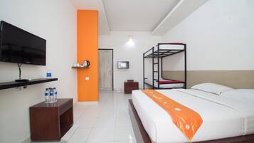 Habitación de hotel con literas, un televisor de pantalla plana, una mesita de madera con botellas de agua y una pared de acento naranja brillante.