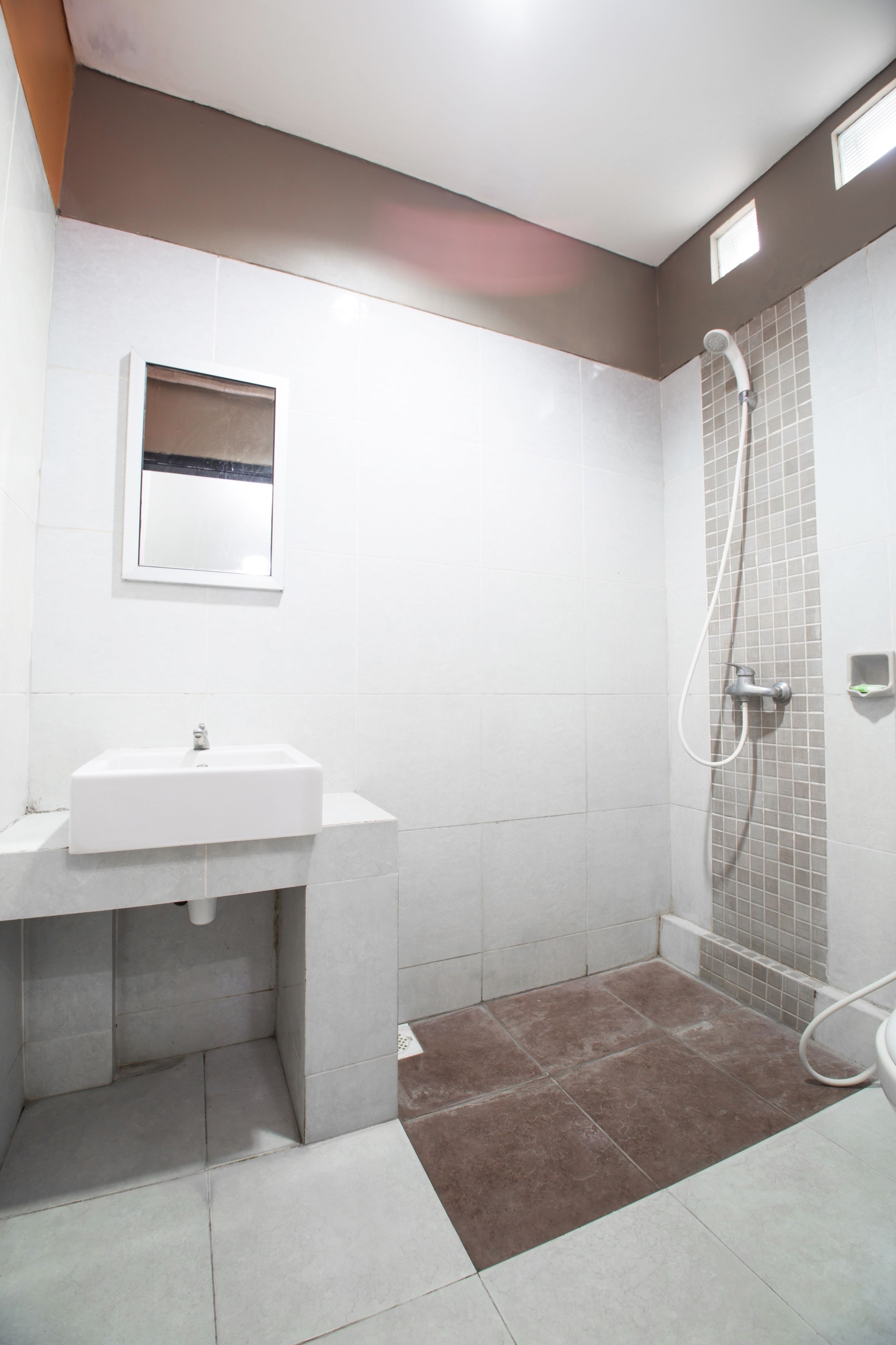 A bathroom with a white sink, a mirror, and a shower area with tiled walls and floor.