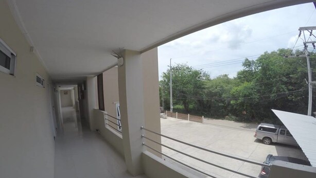 A corridor with a balcony overlooking a parking area and greenery. - SP Place (Chachoengsao)