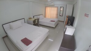 A hotel room with two beds, a desk, a TV, and a mirror. - SP Place (Chachoengsao)