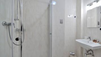 A modern bathroom with a glass-enclosed shower, a white sink, and a mirror.