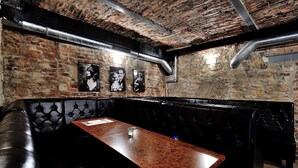 Un restaurante con pared de ladrillo, asientos tipo banqueta de cuero negro y una mesa de madera.
