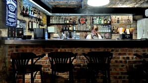 Un bar con pared de ladrillo, estantes llenos de licores y un cantinero.