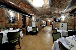 A restaurant with brick walls, wooden floors, and tables set for dining.