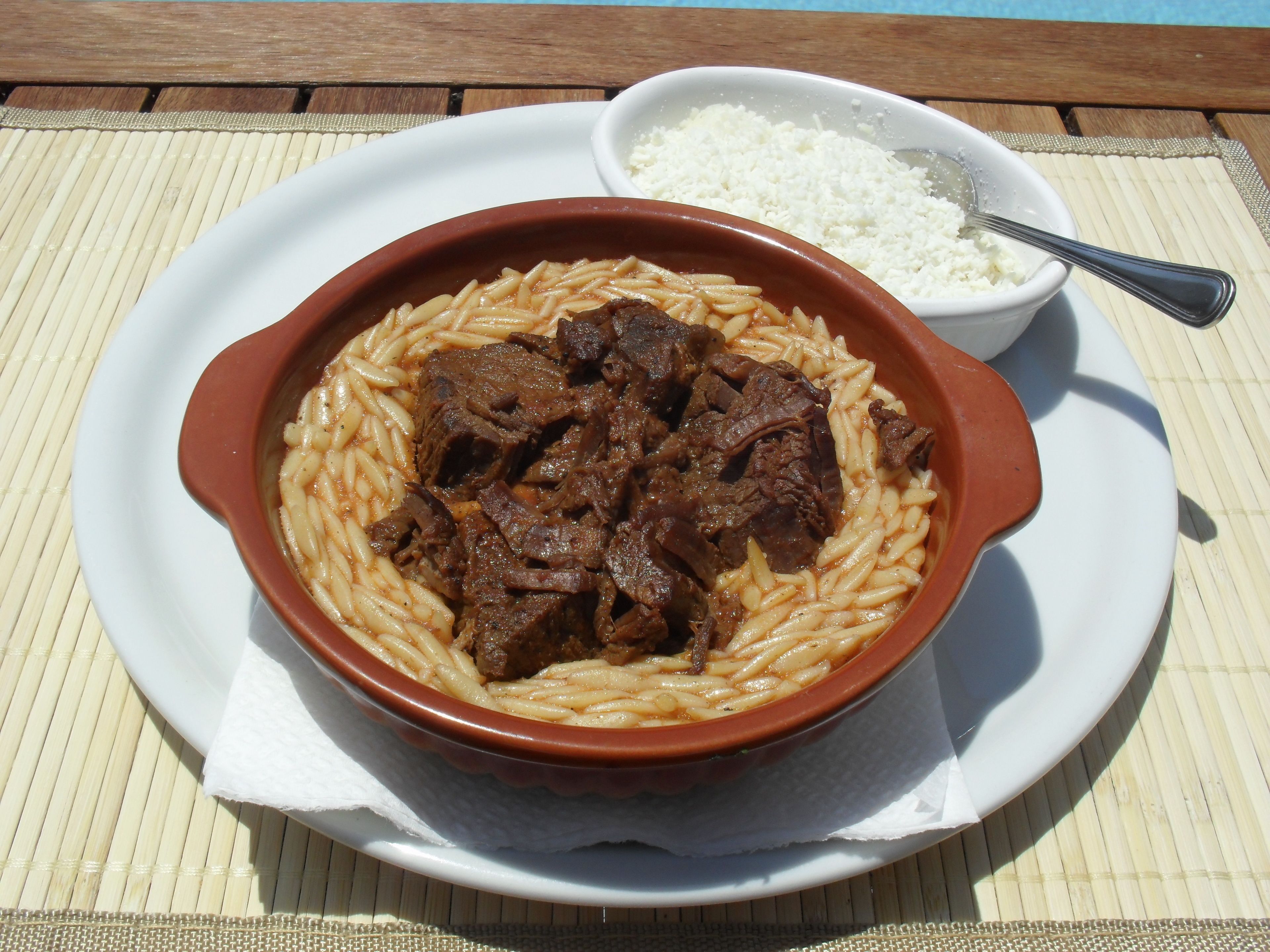 Un bol de pâtes avec de la viande et un petit bol de riz sur une table.