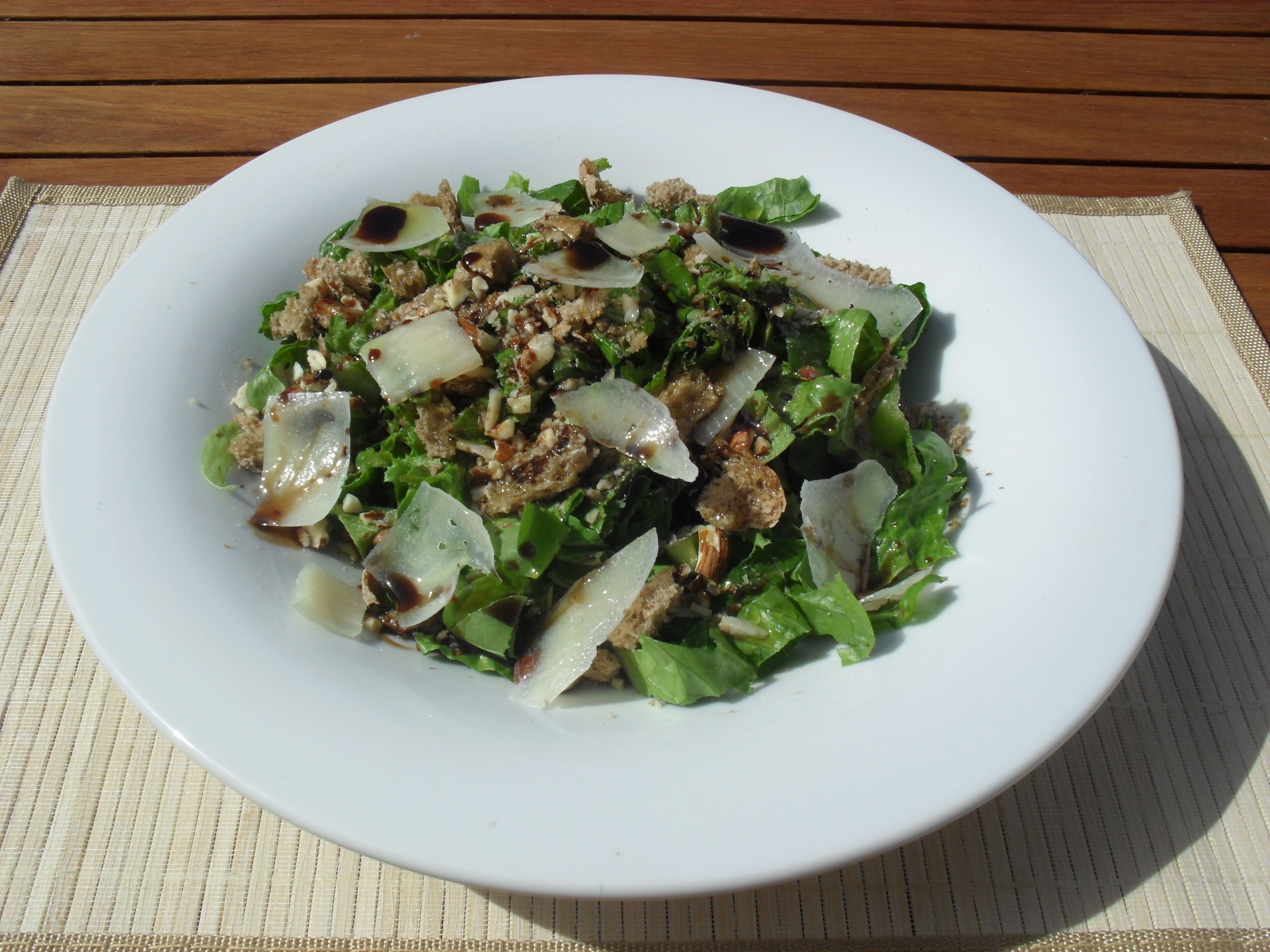A white plate with a salad on a wooden table.