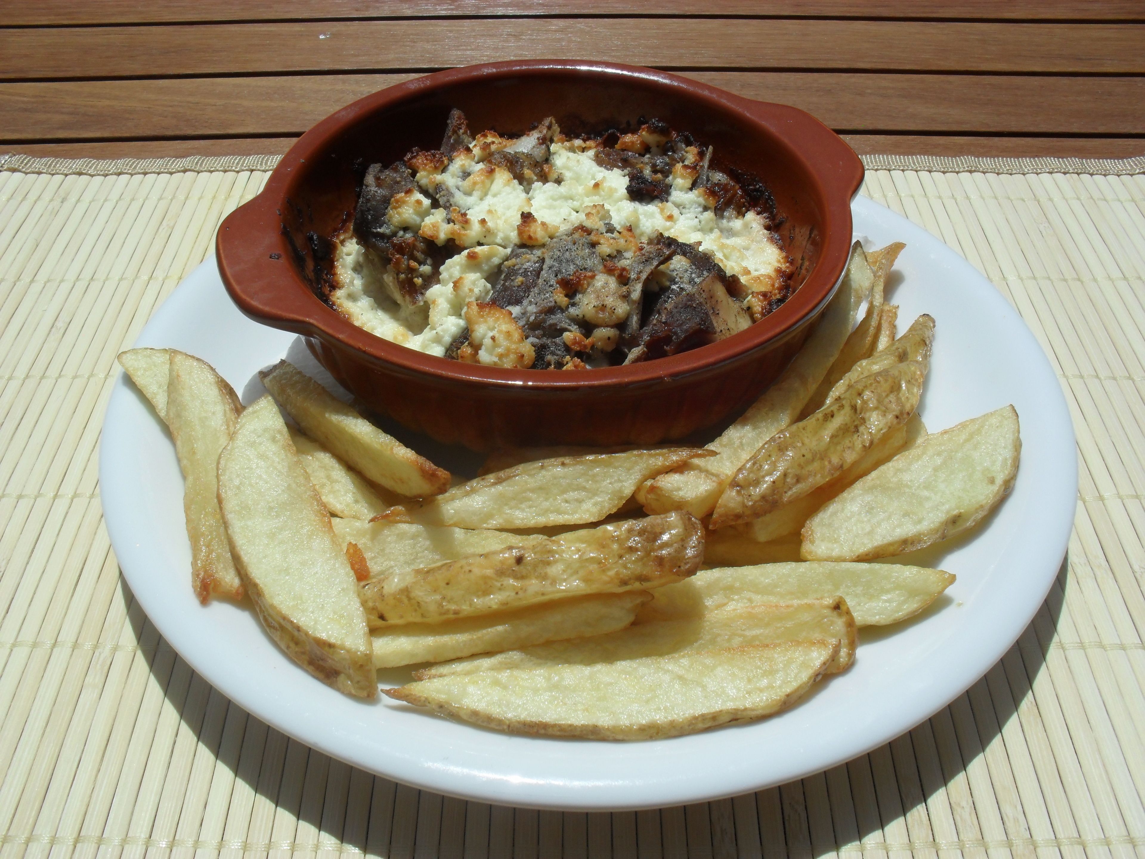 A dish of food in a red bowl, accompanied by French fries on a white plate.