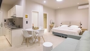 Habitació moderna i ben il·luminada amb una cuineta, zona de menjador i un llit.