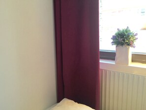A room corner with a window, a radiator, and a potted plant on the windowsill. - Linne Hostel (Gothenburg)