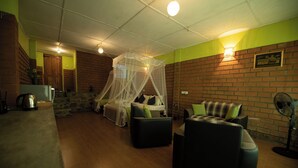 A room with a bed under a canopy, a sofa, a coffee table, and a brick wall. - Ayubo Ella - Bed & Breakfast (Ella)
