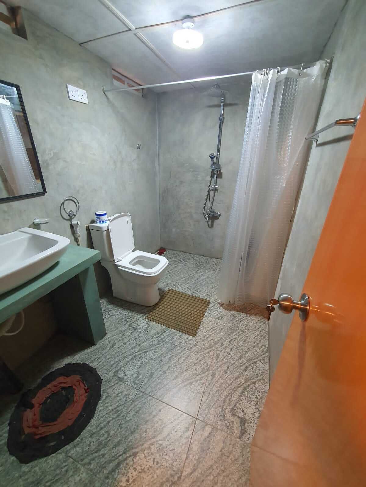 A bathroom with a toilet, sink, shower, and a mirror.