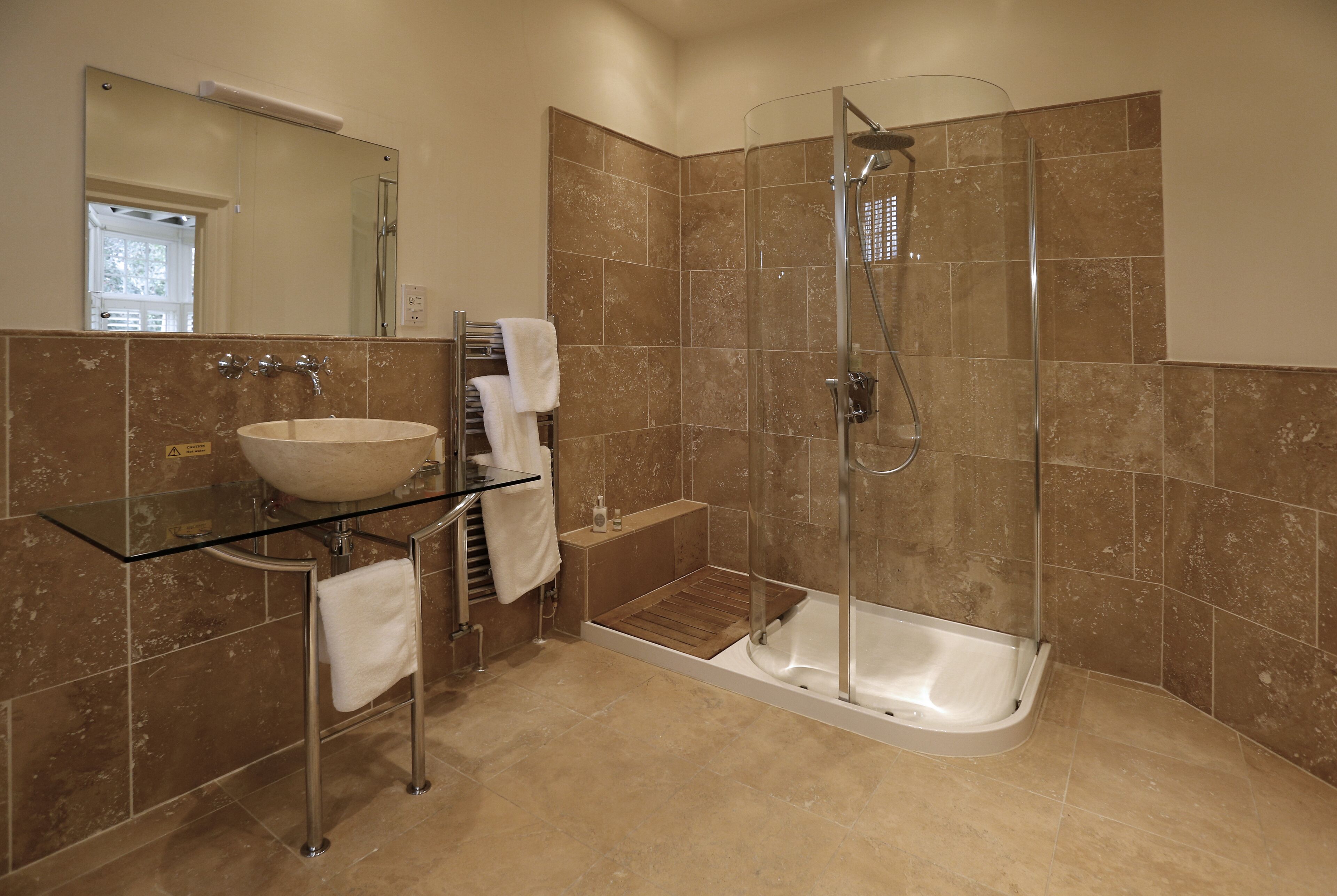 A modern bathroom with a glass-enclosed shower, a standalone bathtub, and a glass-topped sink.