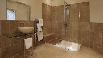 A modern bathroom with a glass-enclosed shower, a standalone bathtub, and a glass-topped sink.