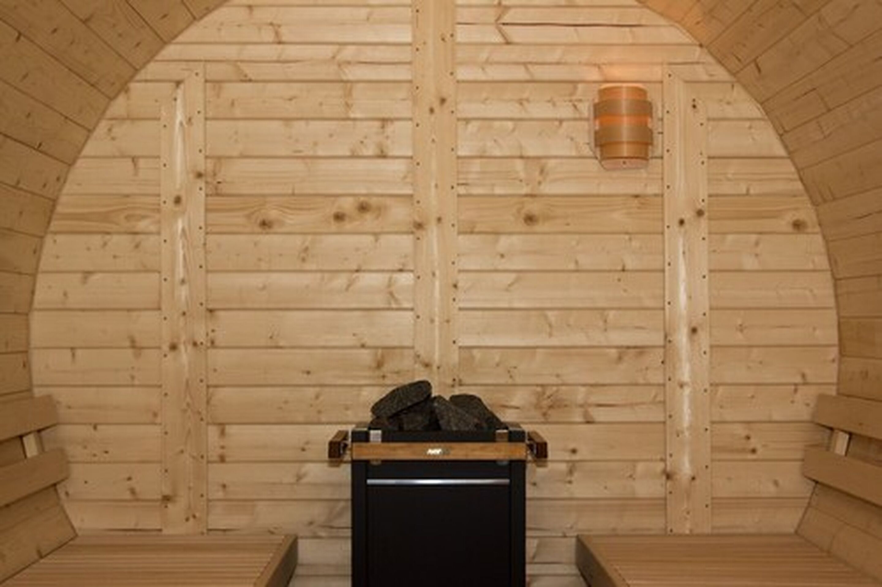A sauna room with wooden walls, a bench, and a heater.