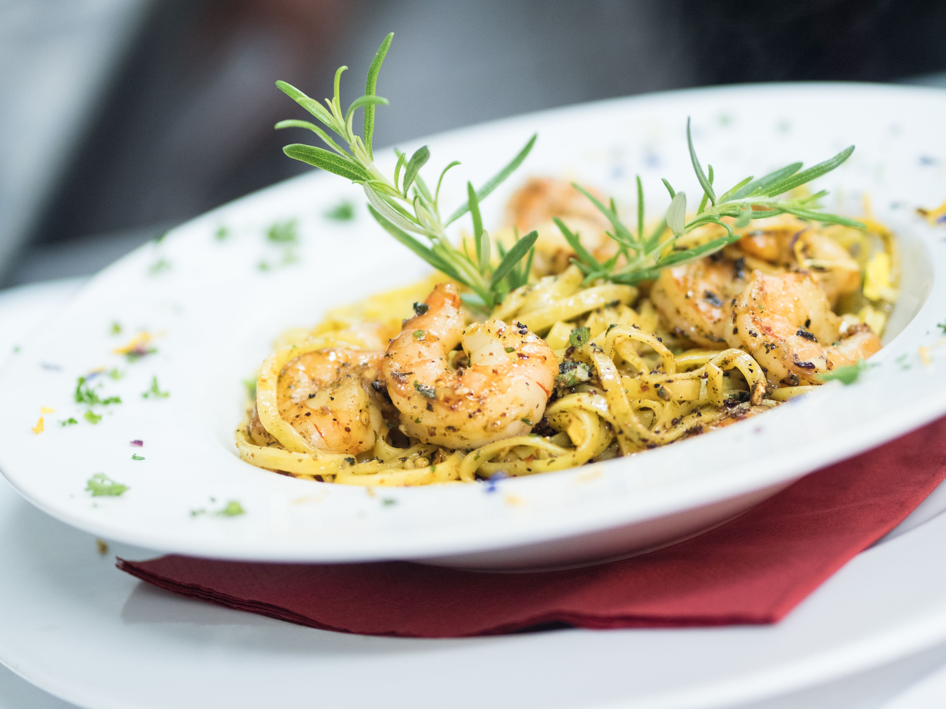 A plate of pasta with shrimp and rosemary garnish.
