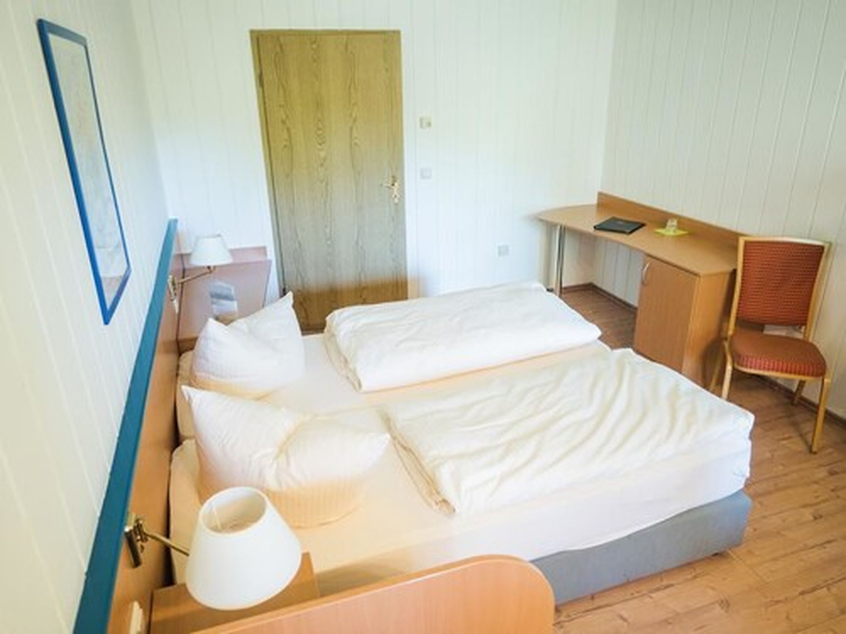A hotel room with a bed, a desk, and a chair.