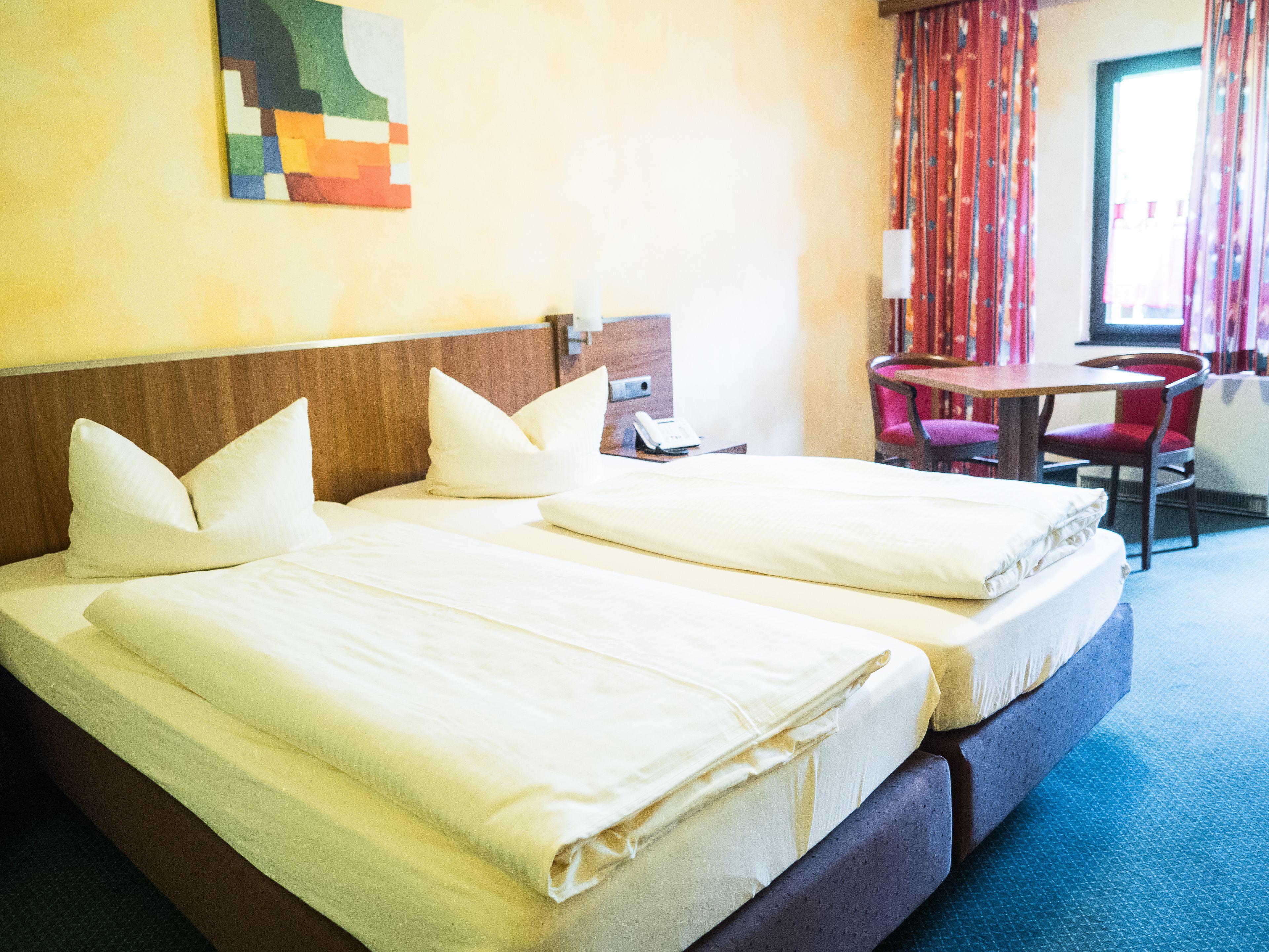 Ein Hotelzimmer mit zwei Betten, einem Schreibtisch und einem Stuhl.