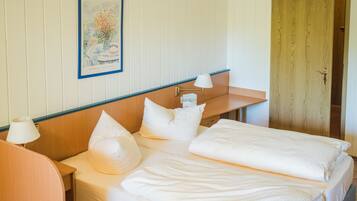 A hotel room with a bed, bedside tables, a lamp, a framed picture on the wall, and a wooden door.