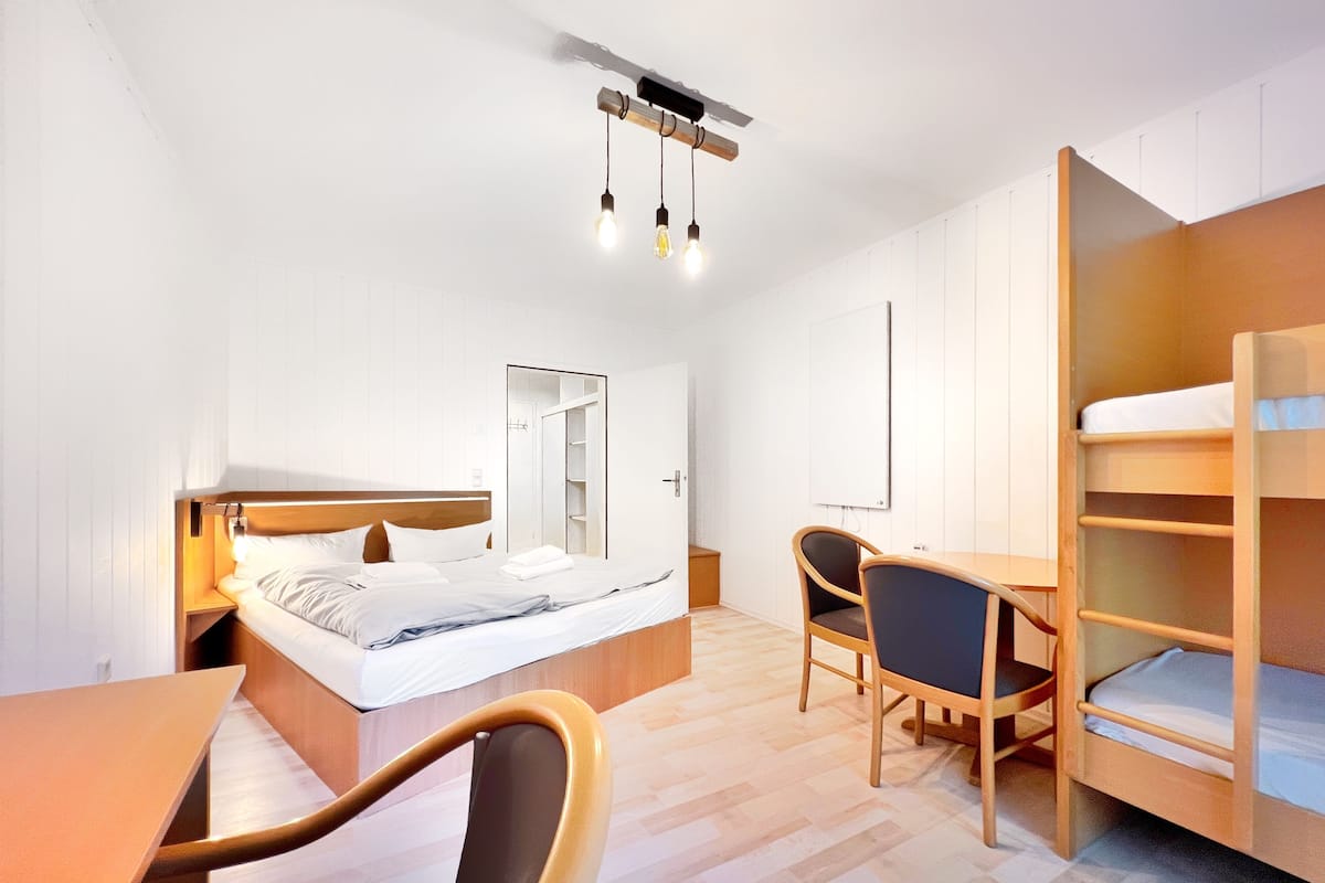 Een kleine hotelkamer met een bed, een bureau, een stoel, een kledingkast en een spiegel.