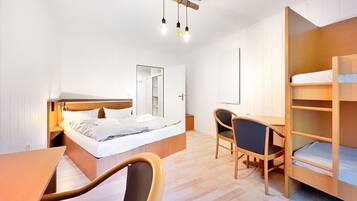 Una habitación de hotel compacta con una cama, un escritorio, una silla, un armario y un espejo.