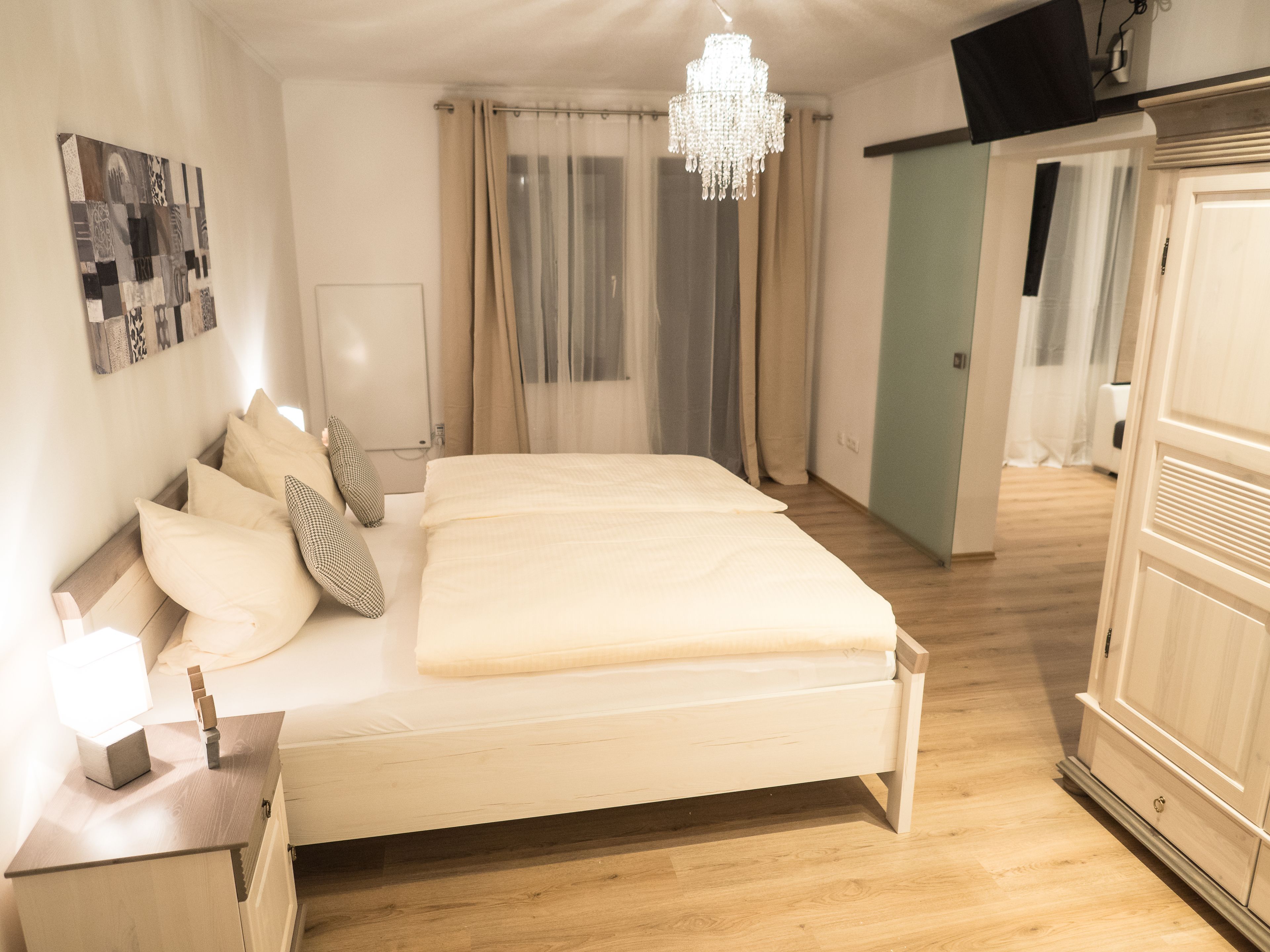 A bedroom with a bed, bedside table, and a chandelier.