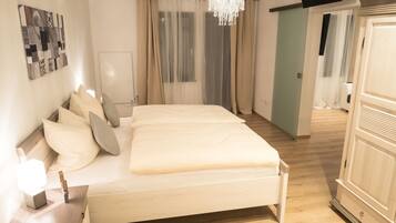 A bedroom with a bed, bedside table, and a chandelier.