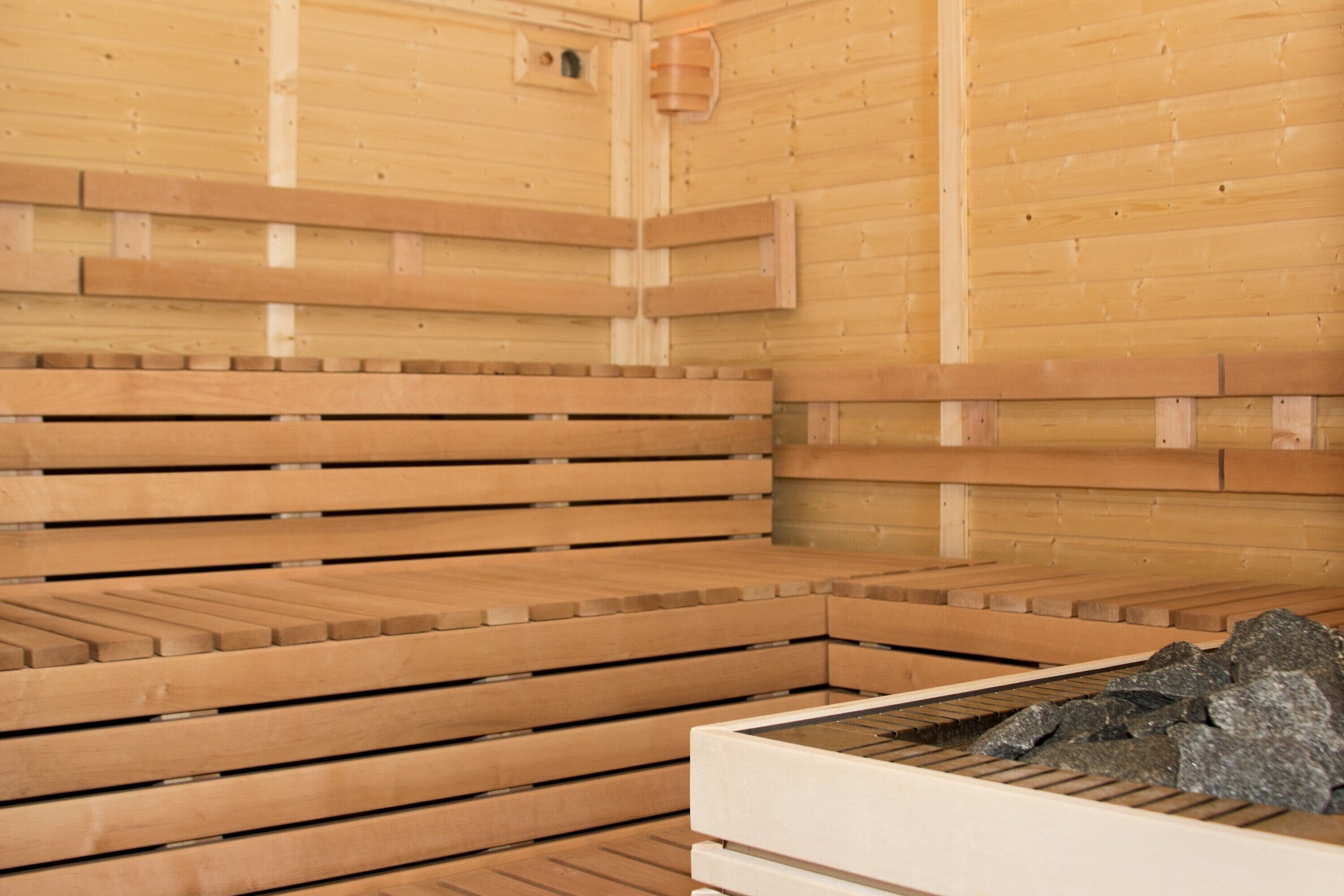 Una sauna con bancos de madera y una pileta de piedra.