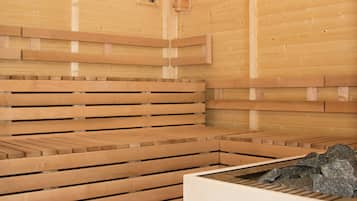 Una sauna con bancos de madera y una pileta de piedra.