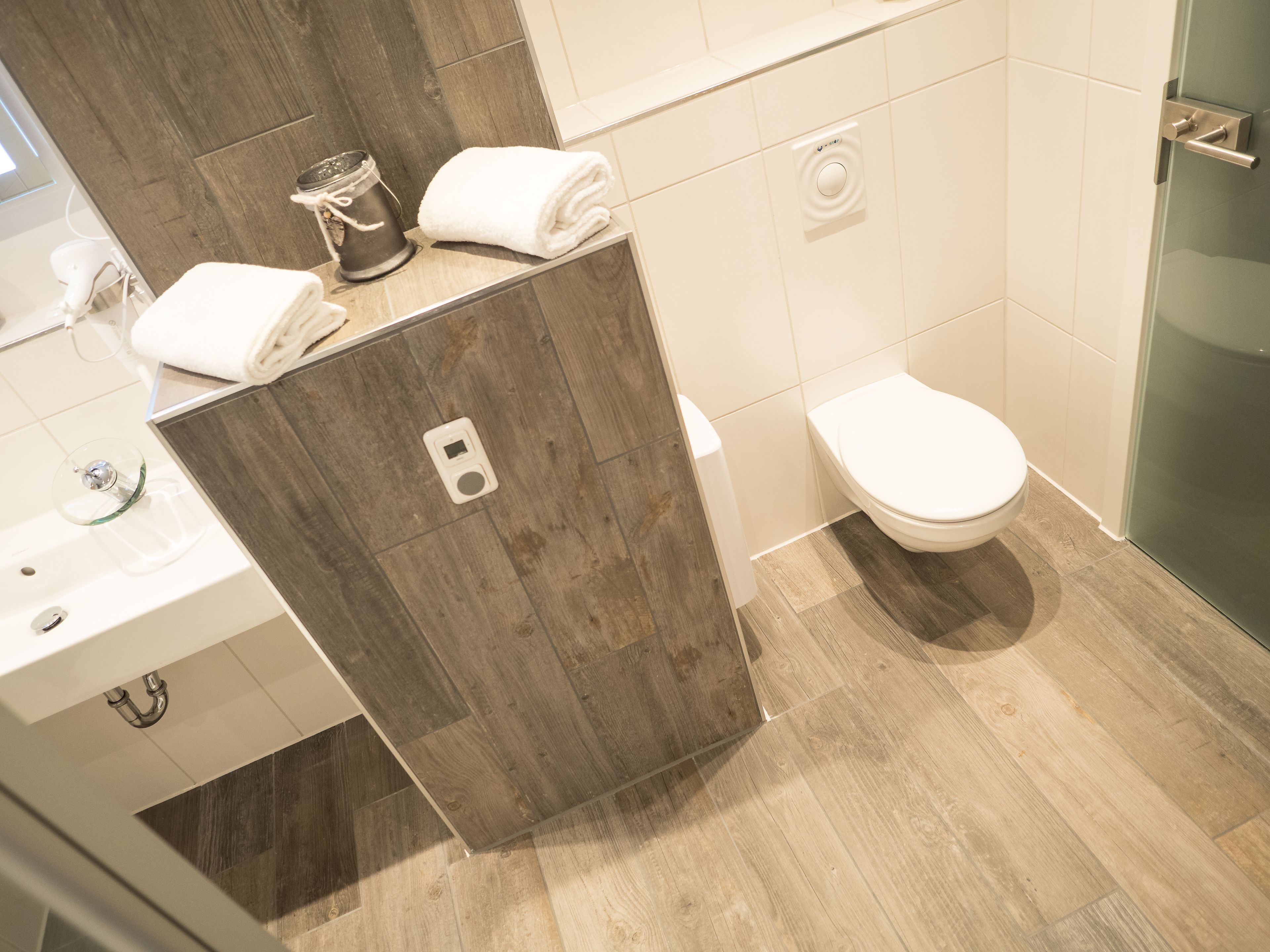 Une salle de bain moderne avec un meuble-lavabo en bois, des toilettes et une douche à parois de verre.