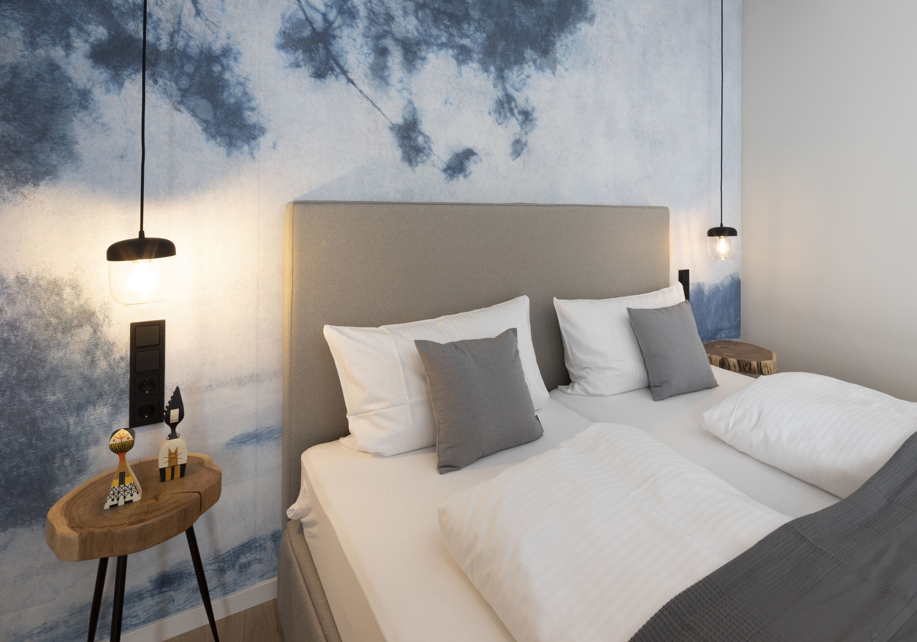 Un dormitorio con una cama grande, dos mesitas de noche y una lámpara fijada en la pared.